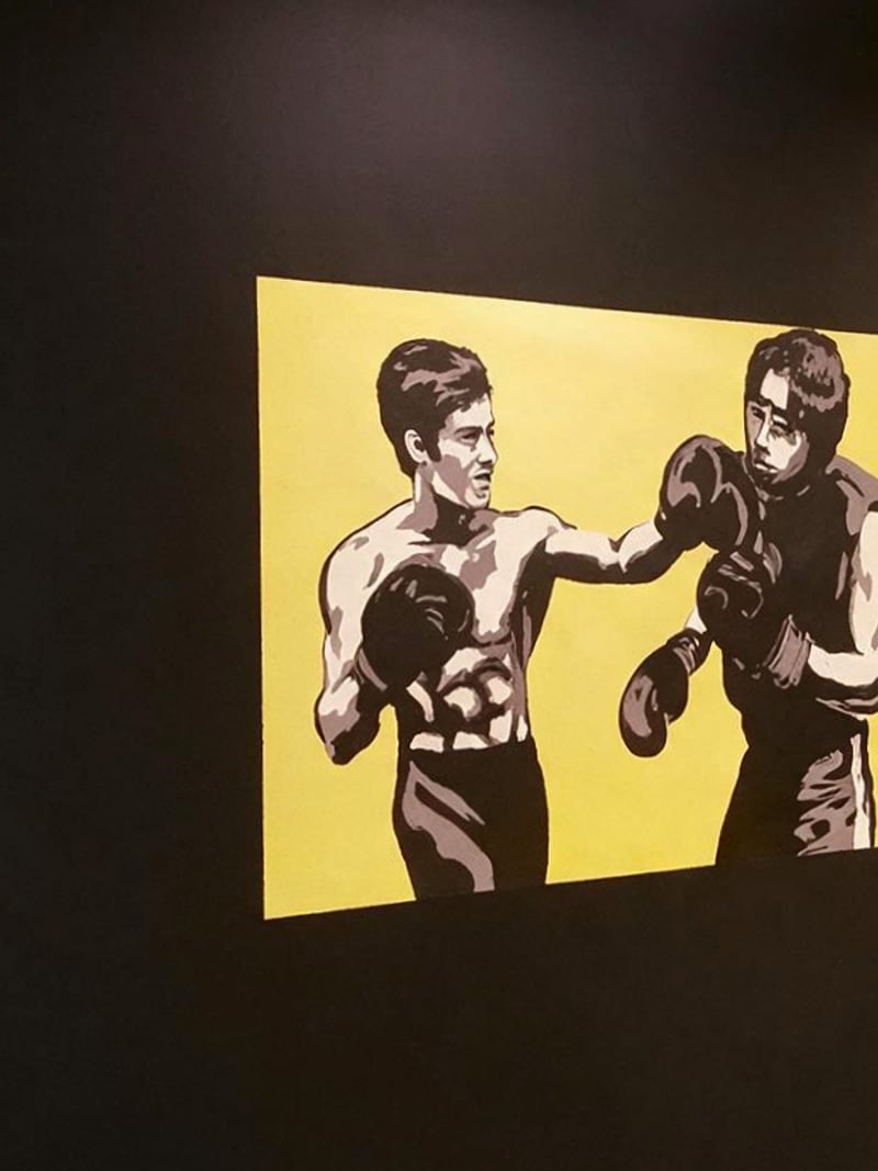 El mural de dos boxeadores pintado sobre la pared negra de la sala