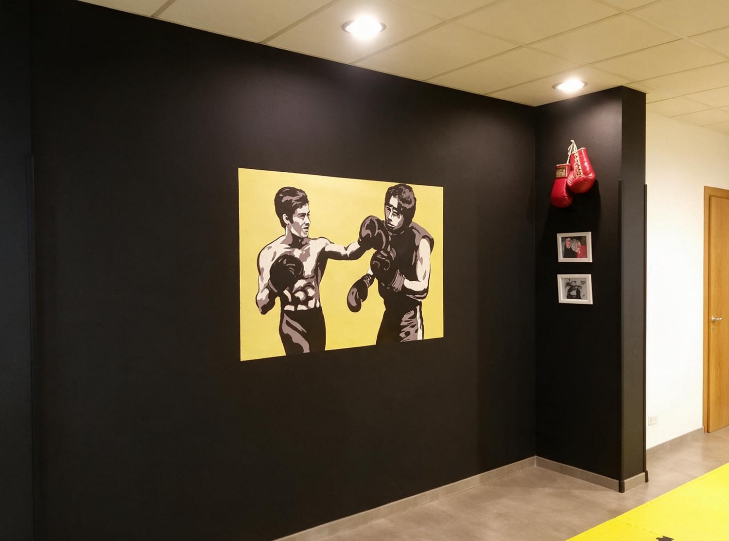 Mural de boxeo y guantes rojos sobre la pared negra del gimnasio